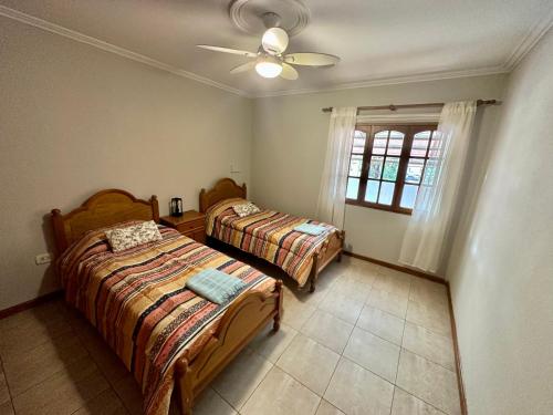 1 dormitorio con 2 camas y ventilador de techo en Cozy Luxury Home Mendoza City en Mendoza