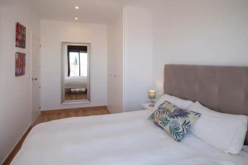 a white bedroom with a large white bed with a pillow at Nuevo apartamento en Benalmádena pueblo con vistas in Benalmádena