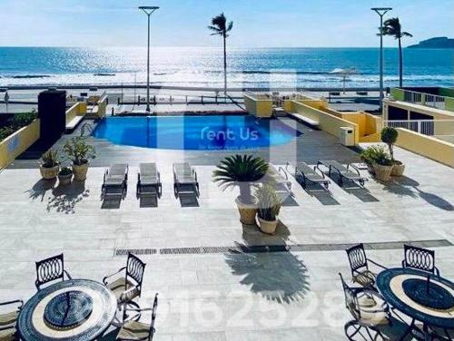 a swimming pool with chairs and the ocean in the background at Condominio Miramar, Mazatlan en malecón frente a la playa in Mazatlán