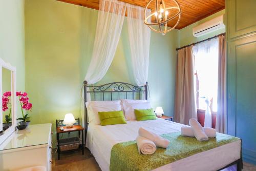 Un dormitorio con una cama con paredes verdes y una lámpara de araña. en Cochelli Upper Pool Walk to beach AC WiFi, en Ágios Stéfanos