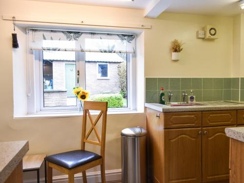 a kitchen with a window and a chair next to a sink at Sandwath in Temple Sowerby