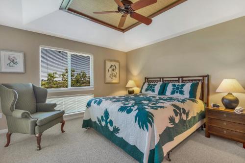 a bedroom with a bed and a chair and a ceiling fan at Palm Villas 2 Bed/2 Bath Loft #F22 in Waikoloa