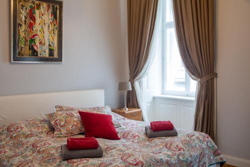 Un dormitorio con una cama con almohadas rojas y una ventana. en Stilvolles Apartment in zentraler Lage, en Viena