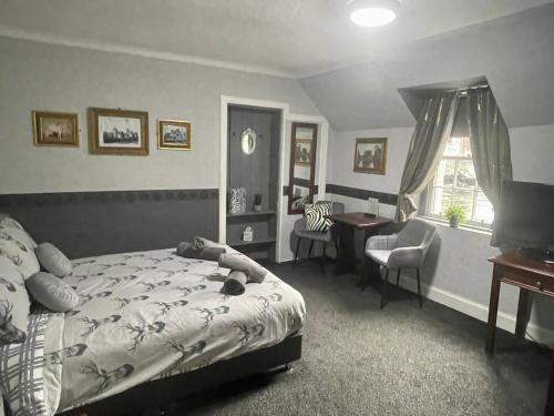 a bedroom with a bed and a desk and a chair at Navaar House Hotel in Penicuik