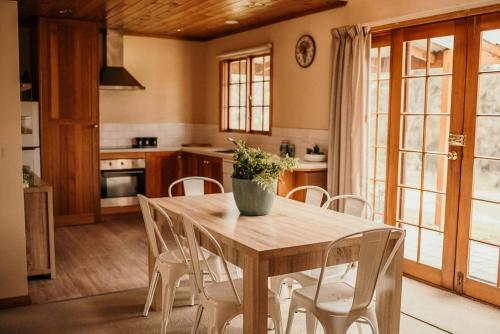 cocina con mesa de madera y sillas blancas en Otago Cottage, en Hobart