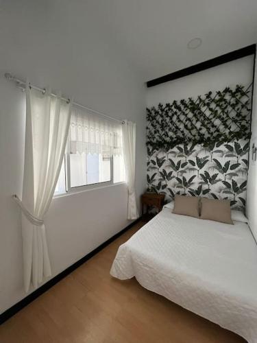Un dormitorio con una cama blanca y una ventana. en Apartamento Plaza Mayor - Torrelavega, en Torrelavega