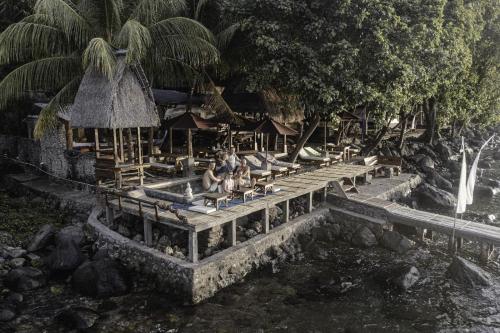 a group of people sitting on benches next to a river at HAPPY DIVE RETREAT fka Ankermi Happy Dive in Hitokalak