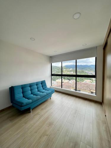 a blue couch in a room with a large window at Loft en Avenida Santander, Vista a las montañas in Manizales