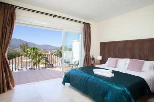um quarto com uma cama grande e uma janela grande em Mediterranean Townhouse CalaGolf em Mijas