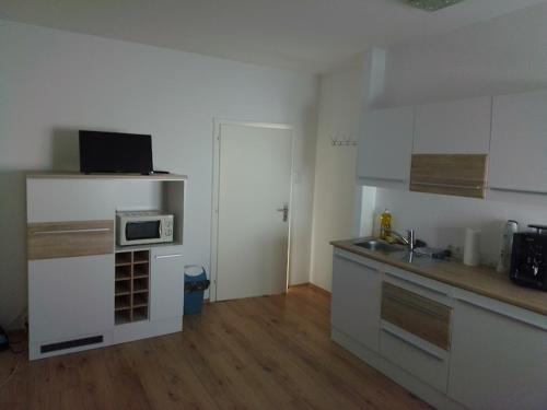 a kitchen with white cabinets and a sink and a microwave at Gästehaus Josef Lang in Andau