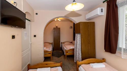 a small room with two beds and a room with a tv at Csillagtúra Panzió in Eger
