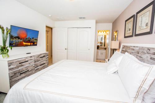 um quarto com uma cama branca e uma televisão na parede em Four Bedroom Close to Disney 5149A em Kissimmee