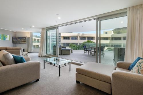 a living room with a couch and a table at Oceanside Apartment with Garden Views in Mount Maunganui