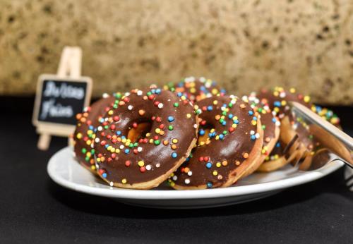 three donuts with chocolate and sprinkles on a plate at Hotel Nogales By Tempo Rent in Santiago