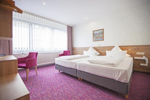 a hotel room with a large bed and two chairs at Am Bismarck in Mannheim