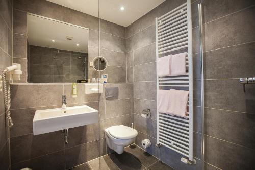 a bathroom with a sink and a toilet and a mirror at Am Bismarck in Mannheim