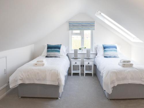 2 bedden in een witte kamer met een raam bij Pebble Cottage in Middleton-on-Sea