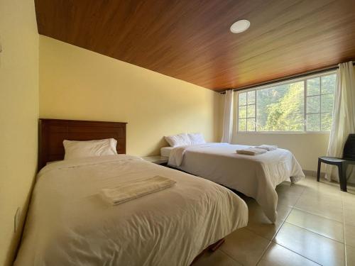 two beds in a room with a window at Penthouse w/rooftop terrace - volcano view in Baños