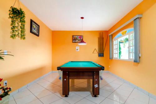 a pool table in a room with orange walls at Pousada Casa da Cidinha in Extrema