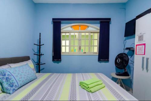 a blue bedroom with a bed with green towels on it at Pousada Casa da Cidinha in Extrema