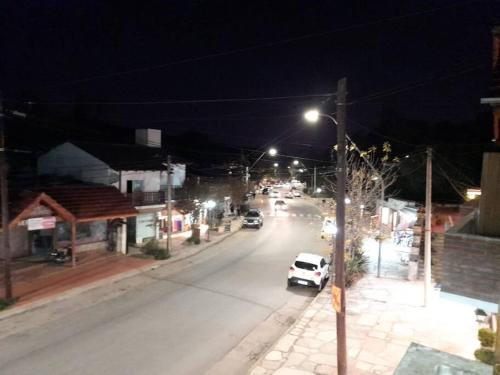 a city street at night with cars driving down the street at Departamento Centrico in Villa General Belgrano