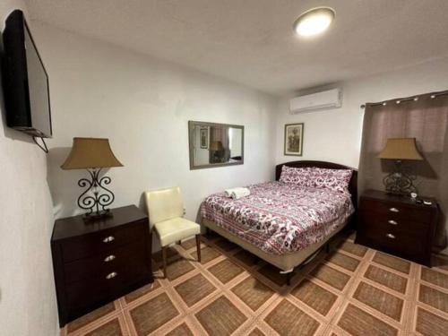 a bedroom with a bed and a tv and a chair at Cepeda Economical 10 BR Compound in San Juan