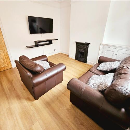 un soggiorno con 2 divani in pelle e una TV di Comfortable 2 Bed House Near City Centre and M1 a Leicester