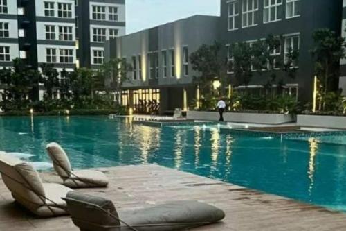 - une piscine avec des chaises longues devant un bâtiment dans l'établissement B2U Residensi Rimbun Kajang 2 Bedrooms, à Kajang