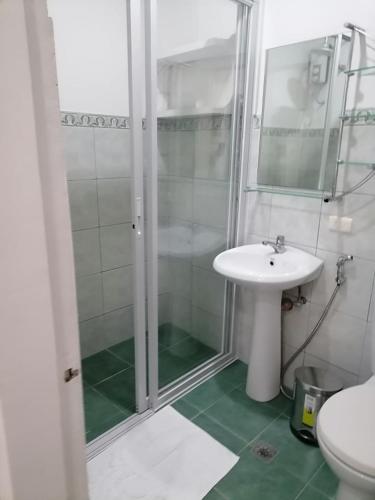a white bathroom with a shower and a sink at Victoria's Inn by Martha Vacation Homes in Boracay