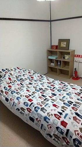 a bedroom with a bed with a comforter on it at Corpo Marika 0 in Hakodate