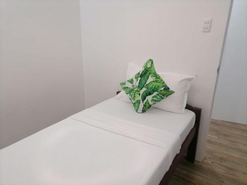 a white bed with a green and white pillow on it at Victoria's Inn by Martha Vacation Homes in Boracay
