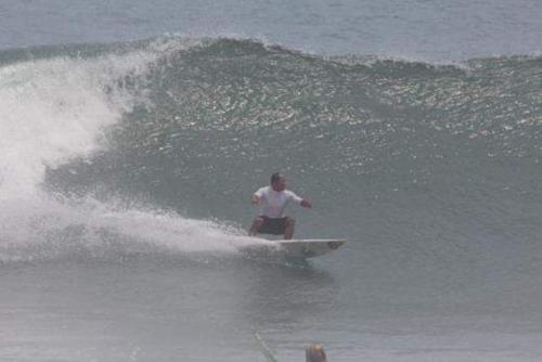 a man riding a wave on a surfboard in the ocean at Big Daddy´s Surfcamp in Pasanggaran