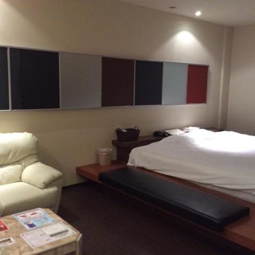 um quarto de hotel com uma cama e um sofá em ホテルオリーブ em Tamaki