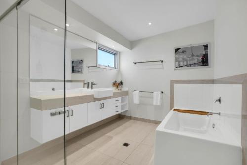 a white bathroom with a sink and a shower at Surf Villa in Warrnambool