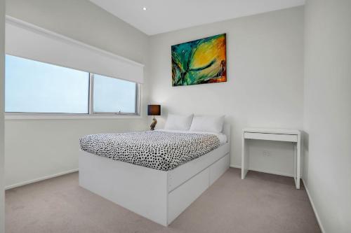 a white bedroom with a bed and a window at Surf Villa in Warrnambool