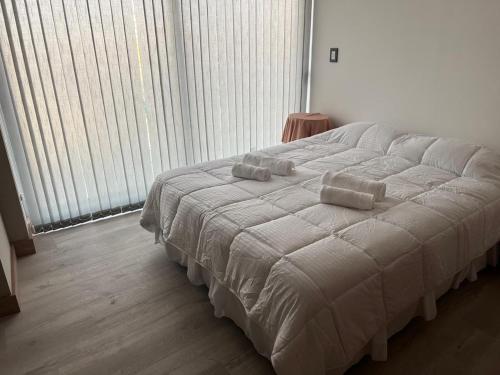 Leloir Premium في Villa Marini: سرير عليه وسادتين في غرفة النوم
