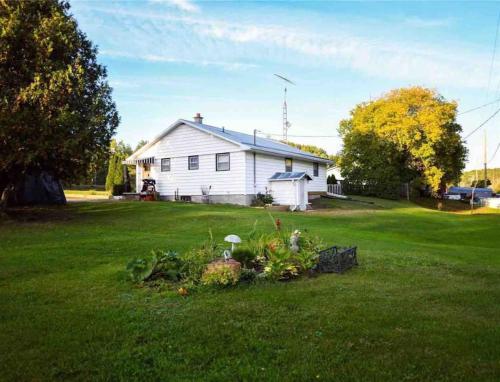 a white house with a windmill in a yard at Private Cottage with Huge Private Dog Park! in Barrys Bay