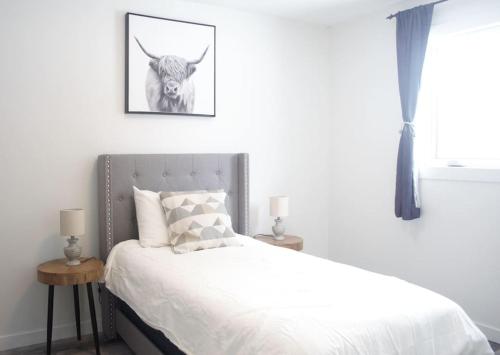 a bedroom with a bed with a cow picture on the wall at Private Cottage with Huge Private Dog Park! in Barrys Bay