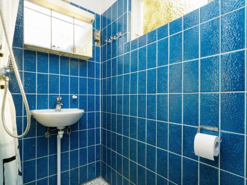 a blue tiled bathroom with a sink and a mirror at Holiday home Højby III in Højby