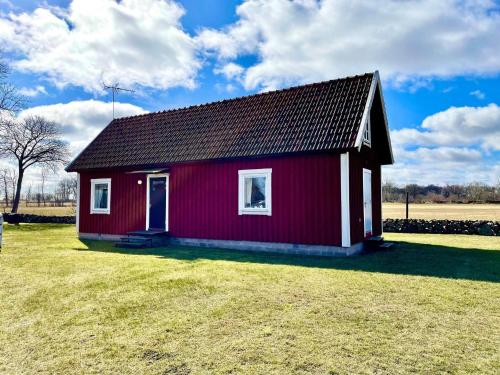 a small red house on a grass field at 5 person holiday home in Löttorp-By Traum in Löttorp