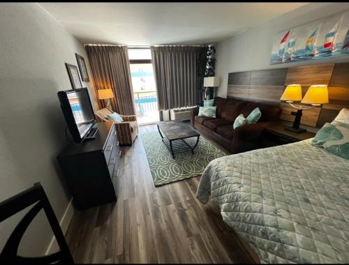 a hotel room with a bed and a couch and a television at Upgraded Studio at Landmark Resort ! 17 pools, lazy rivers, jacuzzis! 814 in Myrtle Beach