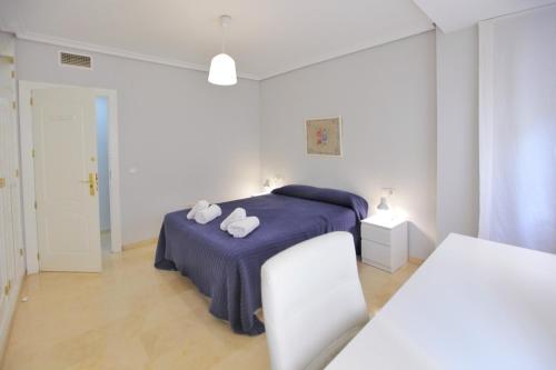 Un dormitorio blanco con una cama con toallas. en Albéniz, en Córdoba