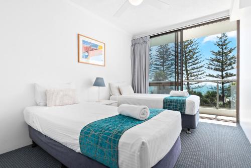 a bedroom with two beds and a large window at Northwind Beachfront Apartments in Mooloolaba