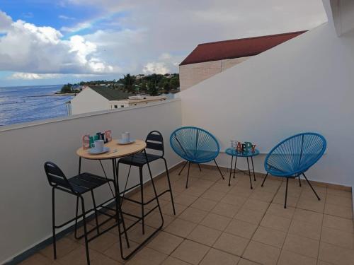un balcone con 2 tavoli, sedie e vista sull'oceano di Cibuqueira numéro 8 , centre ville, vue sur mer, plage à pied a Le Moule