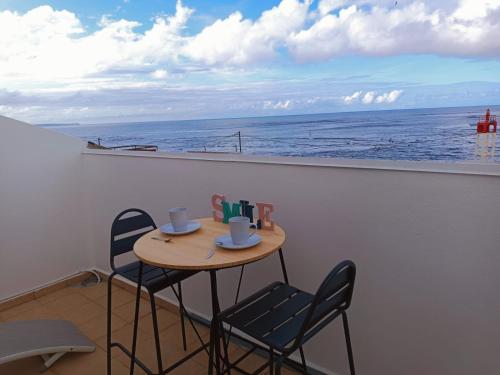un tavolo e sedie su un balcone con vista sull'oceano di Cibuqueira numéro 8 , centre ville, vue sur mer, plage à pied a Le Moule