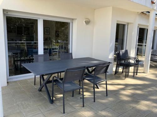 une table noire et des chaises sur une terrasse dans l'établissement Villa Proche Plage avec Jardin, Terrasse et WiFi – La Tranche-sur-Mer - FR-1-22-272, à La Tranche-sur-Mer