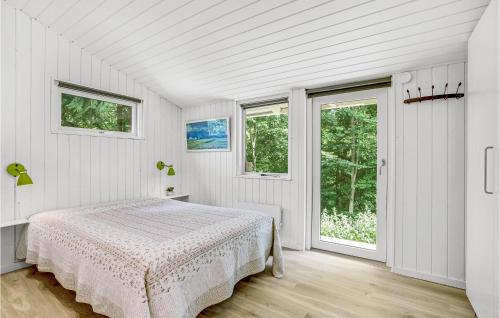 a white bedroom with a bed and two windows at Lille Munkebjerg in Vejle
