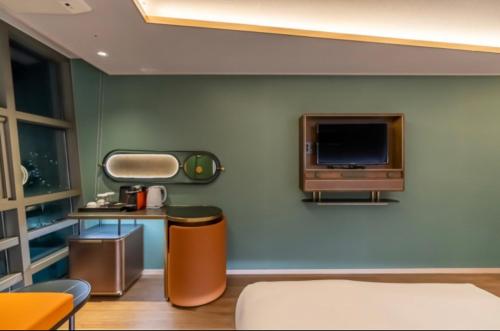 a living room with a tv on a wall at L&L Central Hotel in Jeju