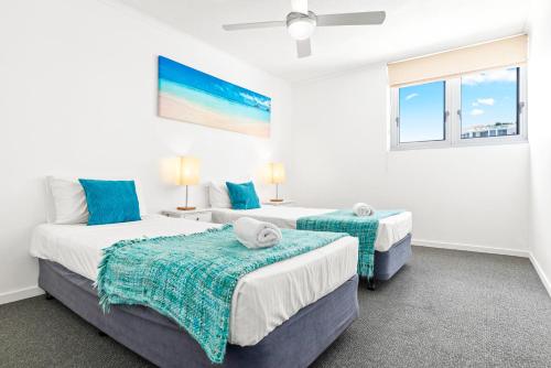 two beds in a room with two windows at Northwind Beachfront Apartments in Mooloolaba