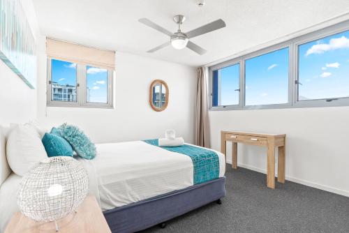 a bedroom with a bed and a table and windows at Northwind Beachfront Apartments in Mooloolaba